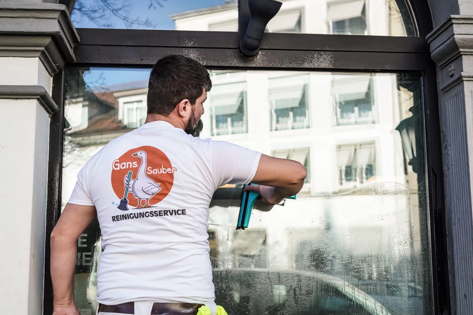 Gans Sauber Mitarbeiter reinigt eine große Glasscheibe